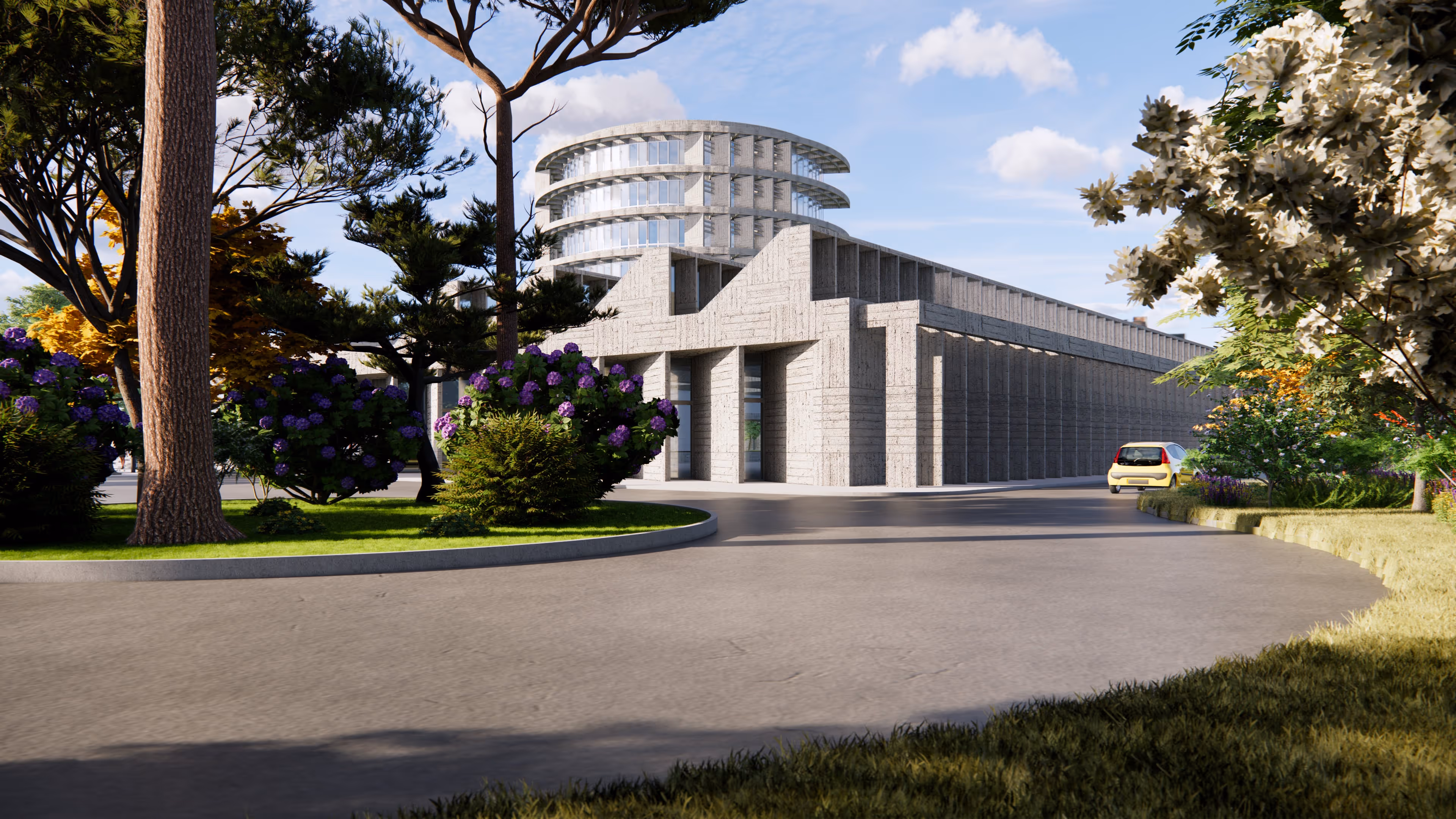 Entrada moderna de edificio con estructura de hormigón y torre circular, rodeada de árboles y arbustos en un día soleado.