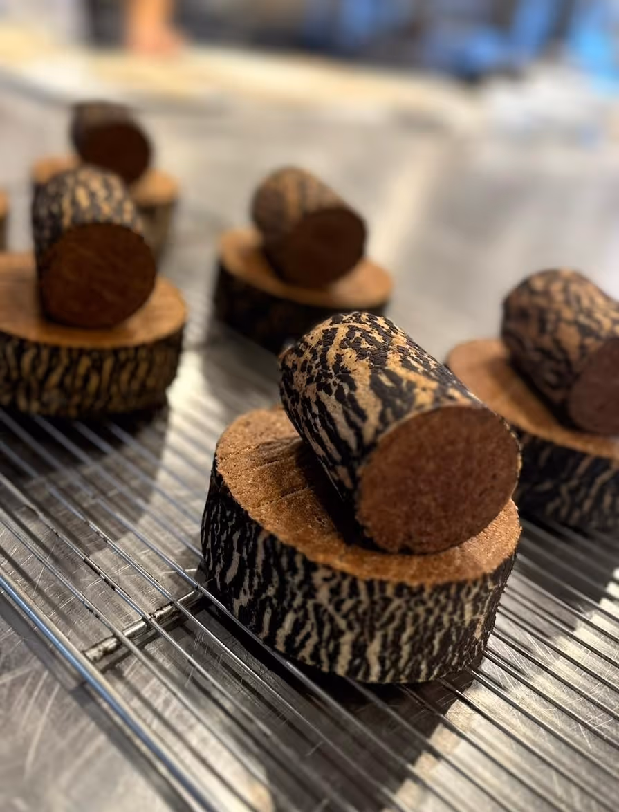 Bolleria con aspecto de troncos de madera cortados en rodajas colocados sobre una rejilla metálica.