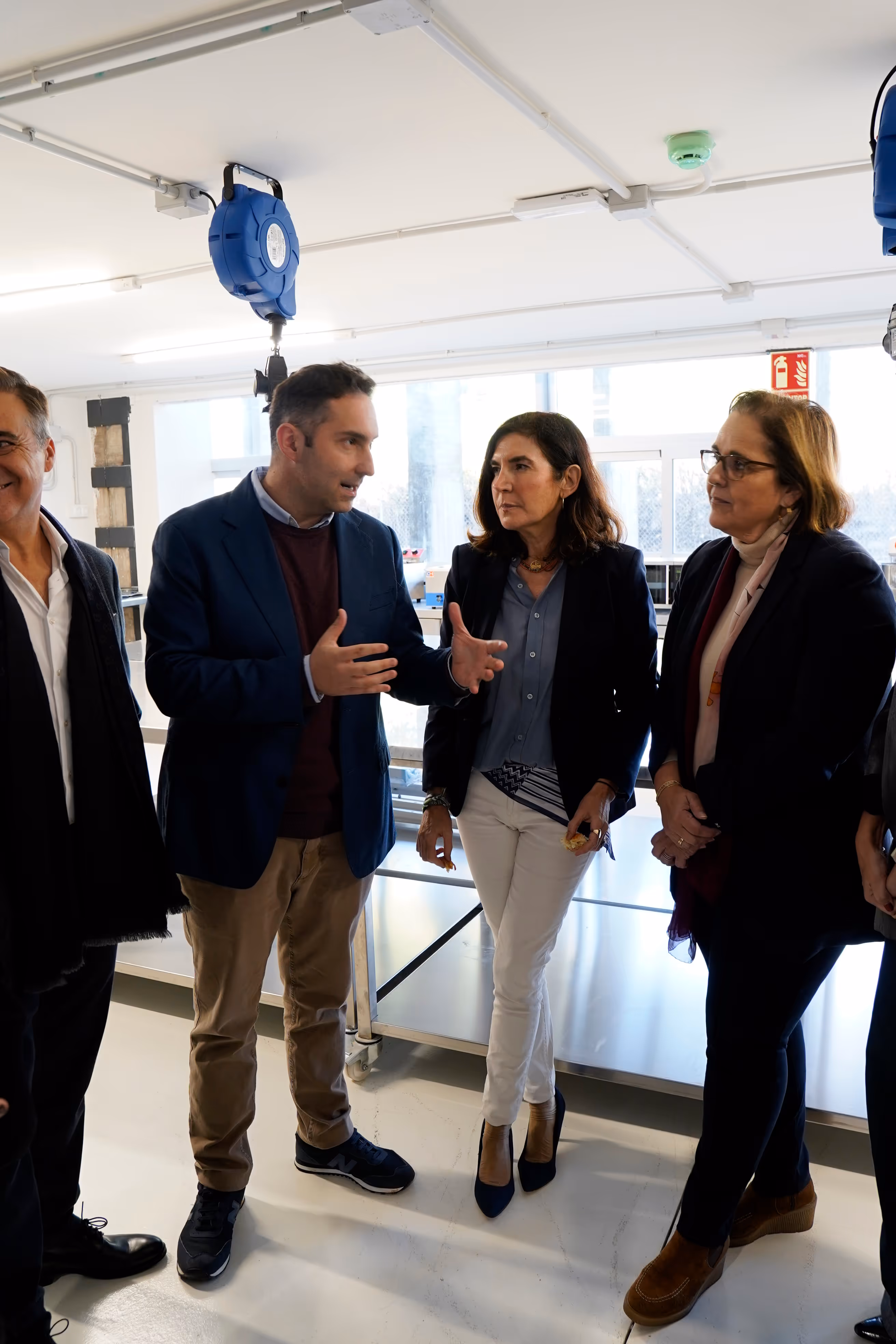 Grupo de cuatro personas conversando en un entorno interior profesional con luz natural.