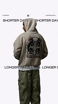 Person wearing a beige hoodie with a black graphic and the text 'RELEASE THE MONKS' on the back, paired with green cargo pants.