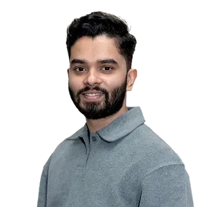 Smiling man with dark hair and beard wearing a gray collared shirt against a transparent background.