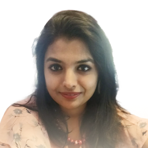 Portrait of a smiling woman with long dark hair wearing a light-colored floral top and a beaded necklace.
