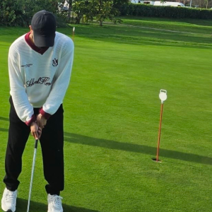 Golfer preparing to putt on a green near the hole flagstick.