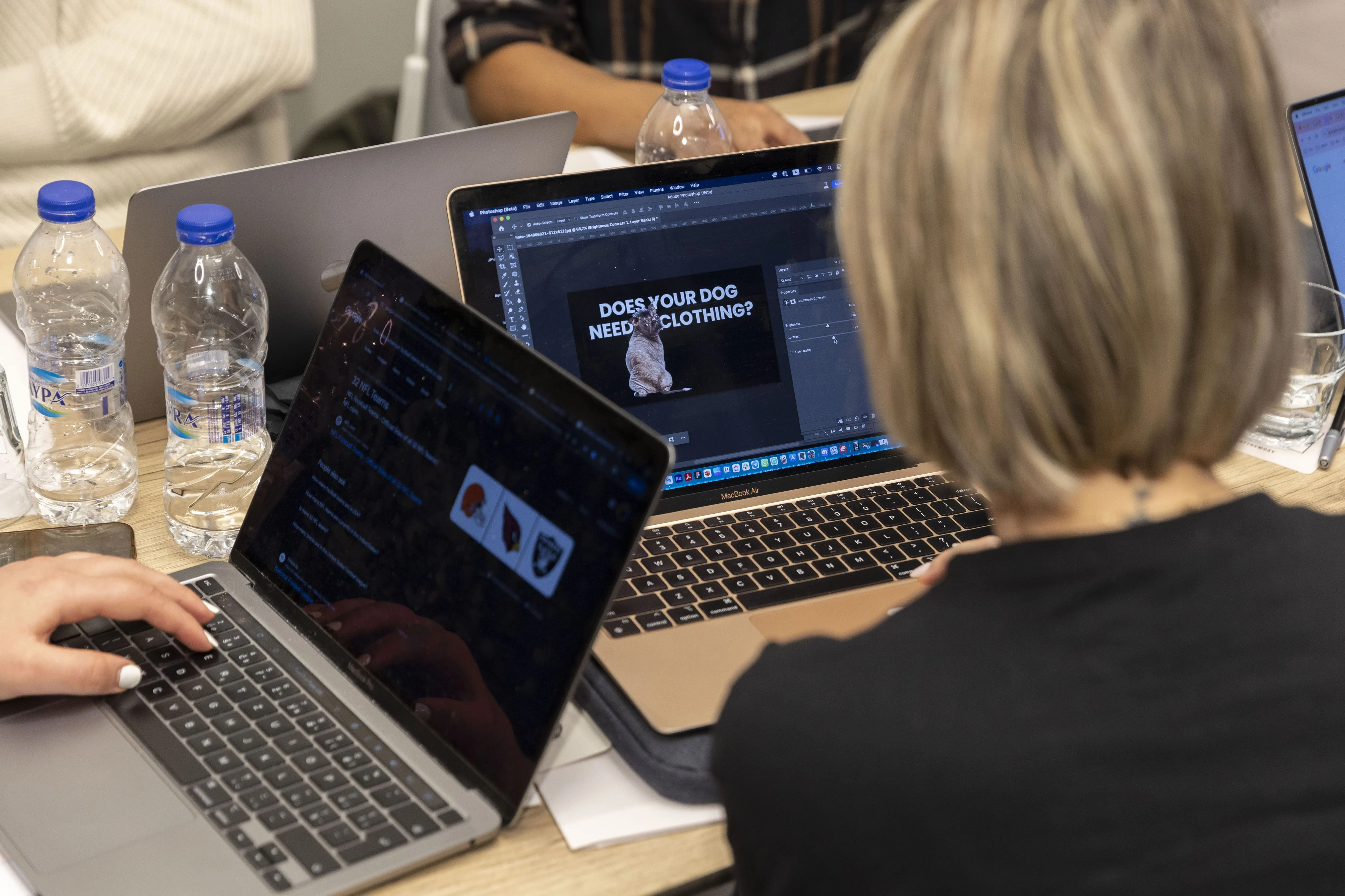 A person working on a laptop displaying a Photoshop project with the text 'DOES YOUR DOG NEED CLOTHING?' and an image of a dog.