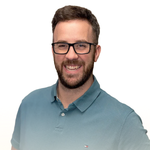 Smiling man with beard and glasses wearing a teal polo shirt.