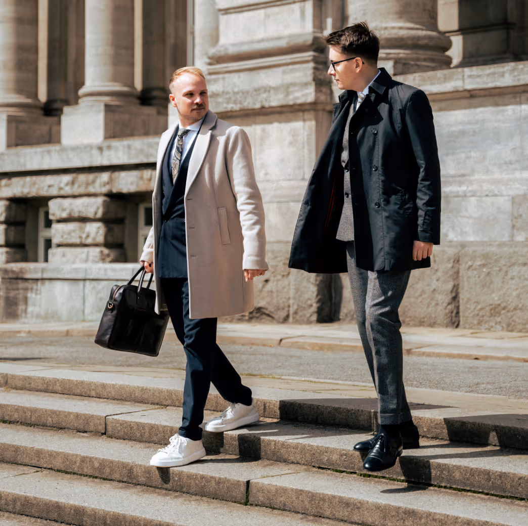 Aufnahme von Rechtsanwalt Alexander Schlüter und Rechtsanwalt Jonas Meese gehend auf den Stufen des Hanseatischen Oberlandesgerichts Hamburg