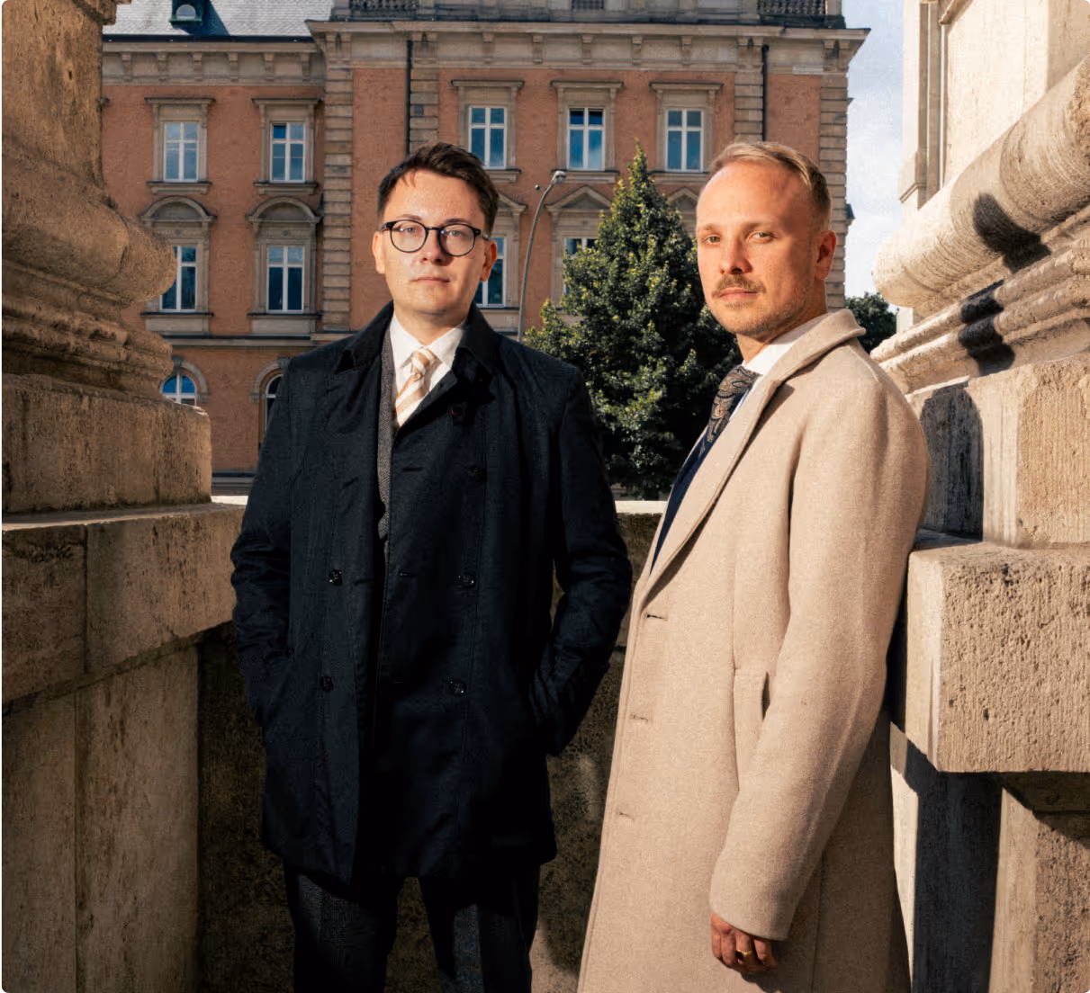 Aufnahme von Rechtsanwalt Alexander Schlüter und Rechtsanwalt Jonas Meese stehend auf den Stufen des Hanseatischen Oberlandesgerichts Hamburg