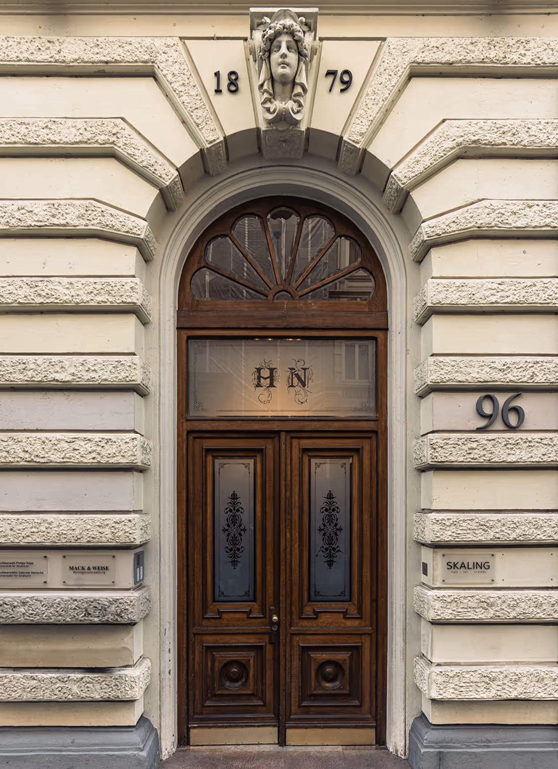 Fassade eines Altbau-Gebäudes mit verzierter Fassade und einer großen Eingangstür aus dunklem Holz