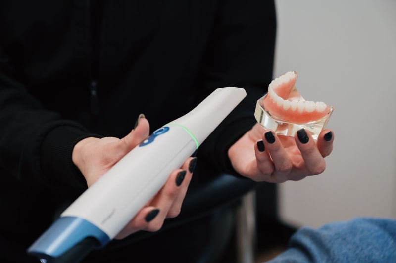 Dentist explaining dental model and treatment options to patient in exam room