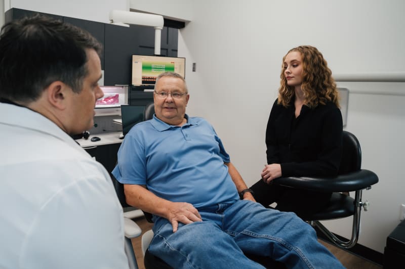 Female dentist discussing treatment plan with male patient in dental chair