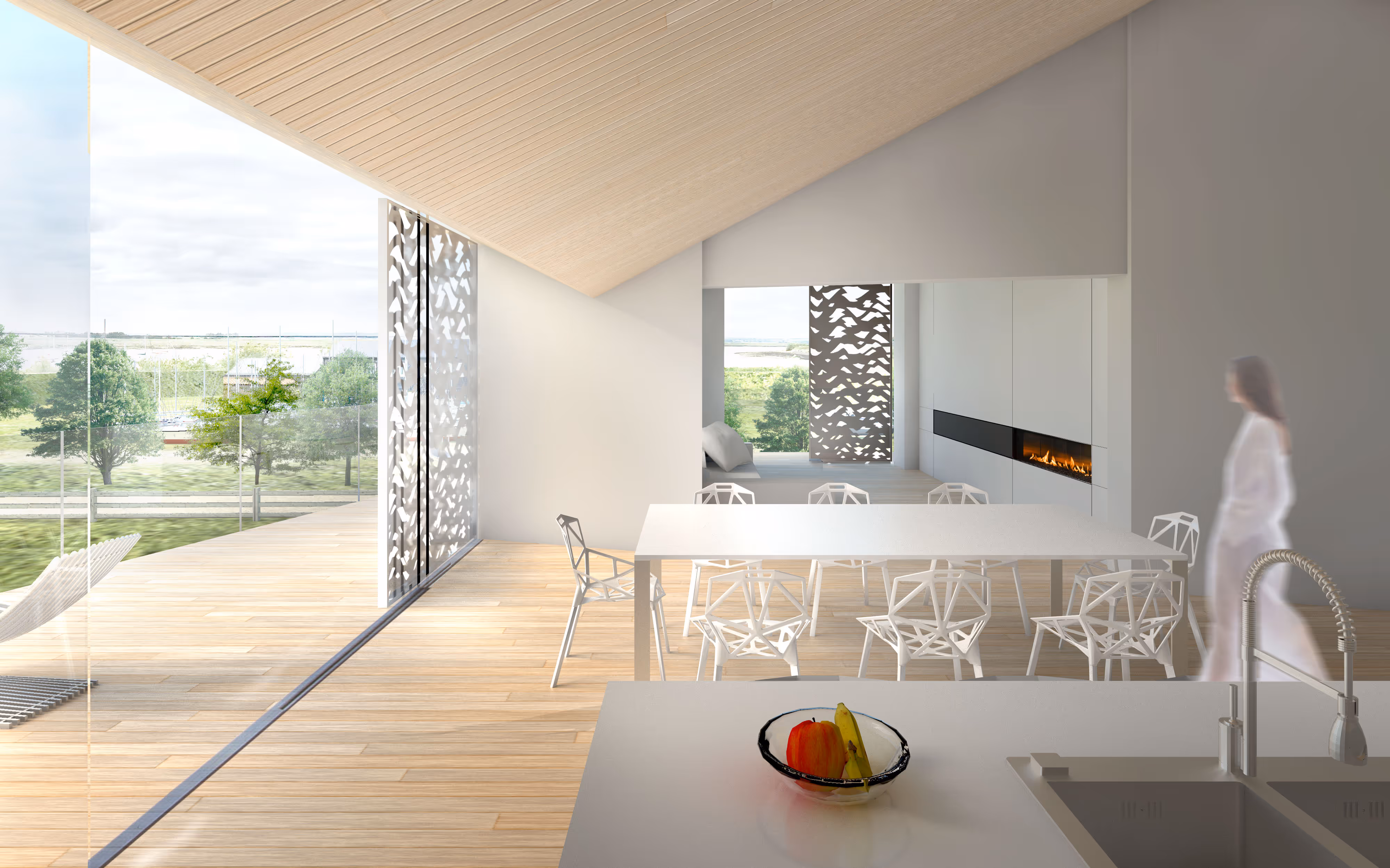 Modern bright dining area with white geometric chairs around a table, a fruit bowl on the kitchen island, a fireplace, and large glass windows showing an outdoor landscape.
