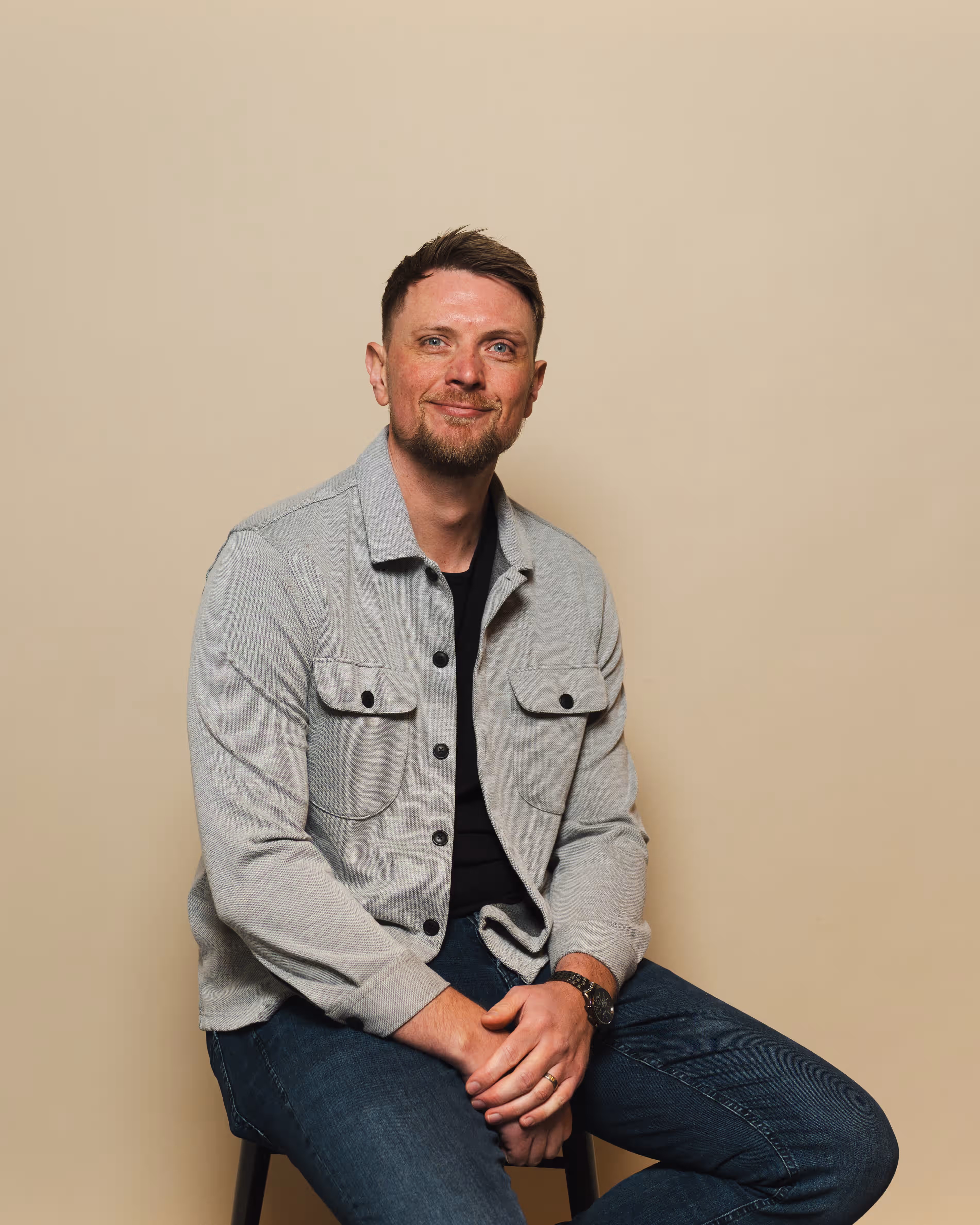Chris Archer seated in a grey jacket against a plain cream backdrop
