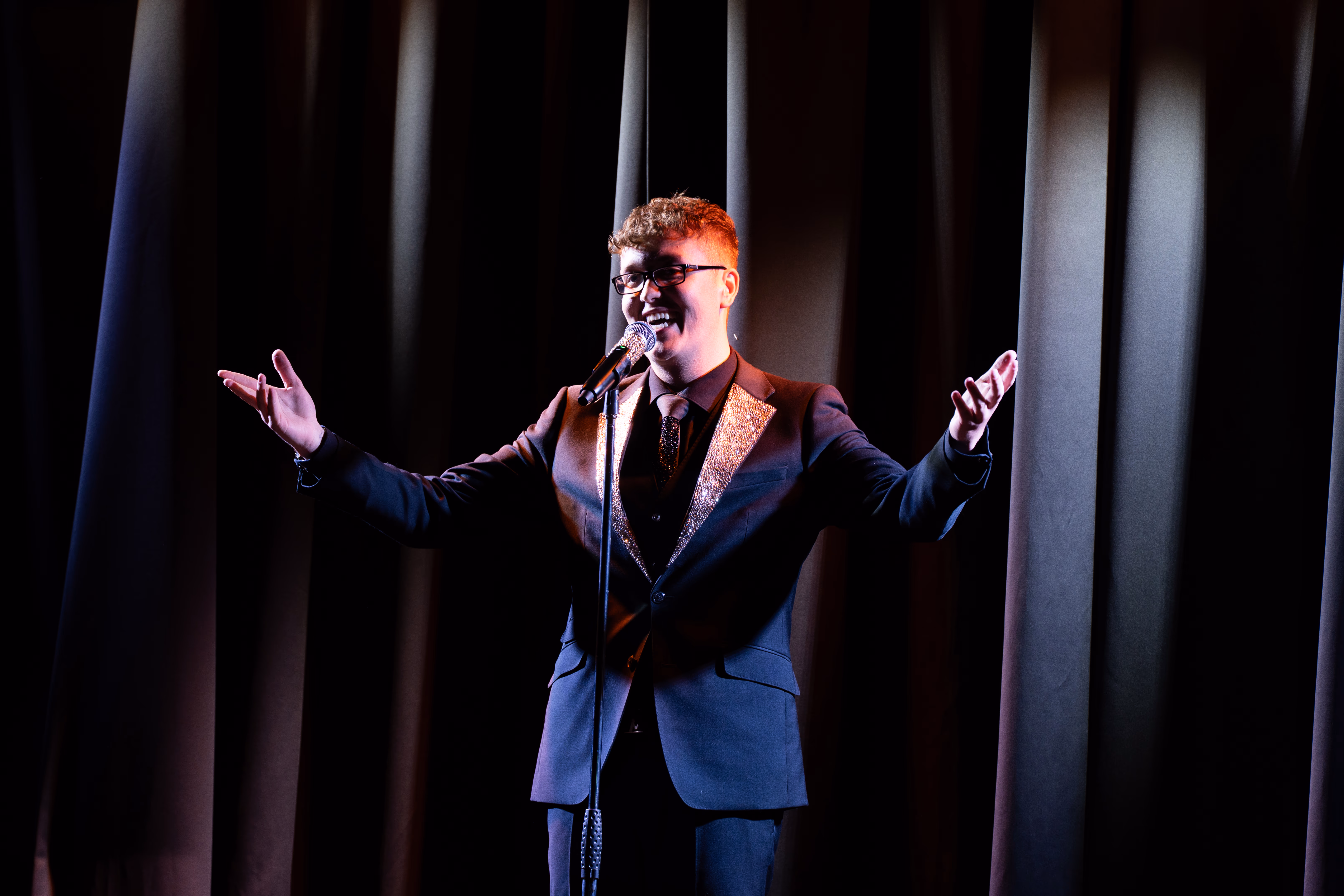 Callum White performing on stage with his arms outstretched