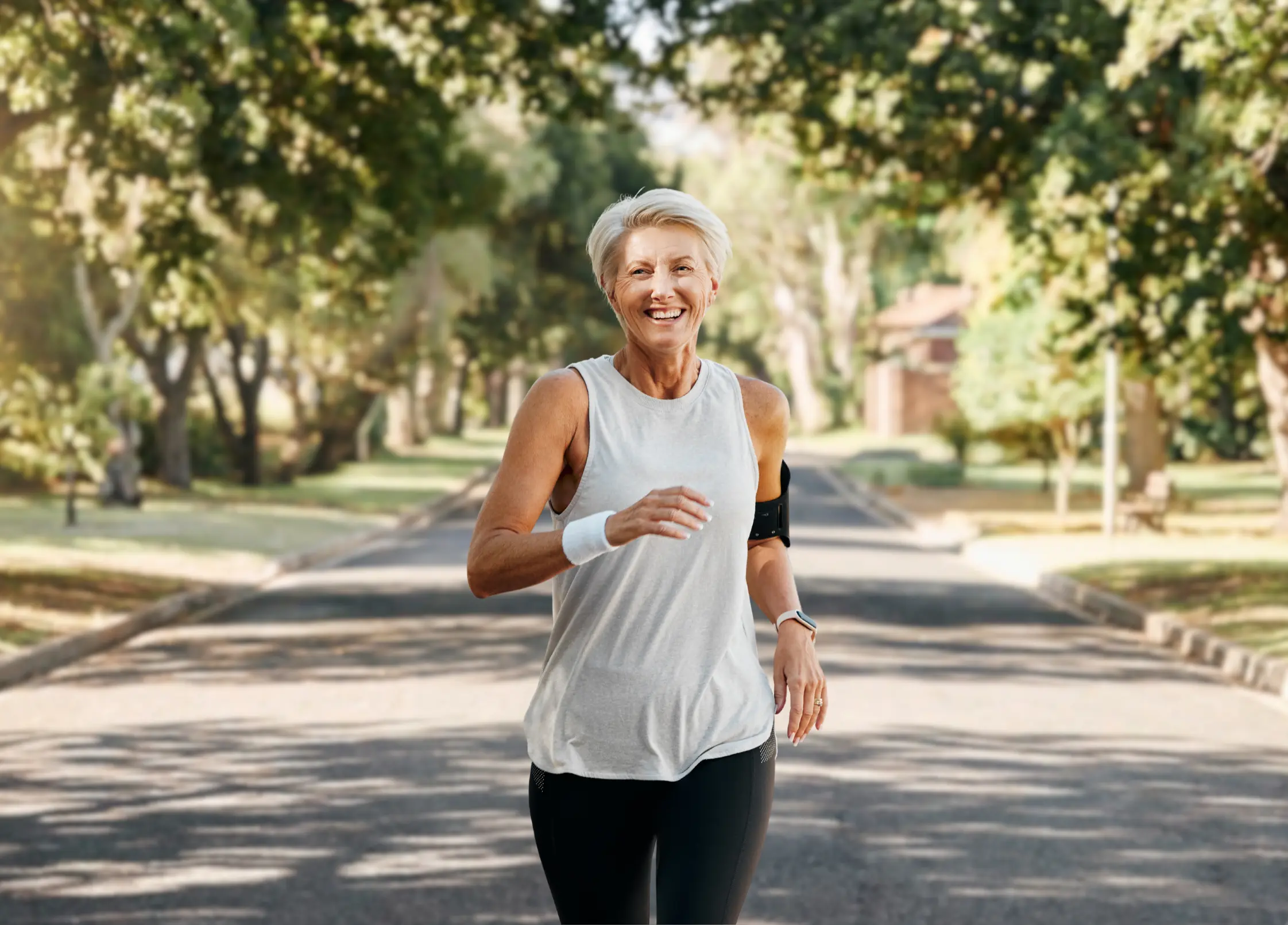 Two older adults jogging together along a tree-lined path on a sunny day.