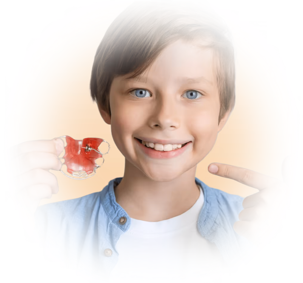 Junge mit herausnehmbarer Zahnspange zeigt stolz sein Lächeln – kindgerechte Kieferorthopädie und frühe Zahnkorrektur.