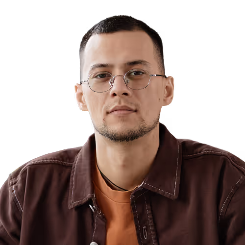 Man with short dark hair, glasses, and a trimmed beard wearing a brown jacket and orange shirt against a transparent background.