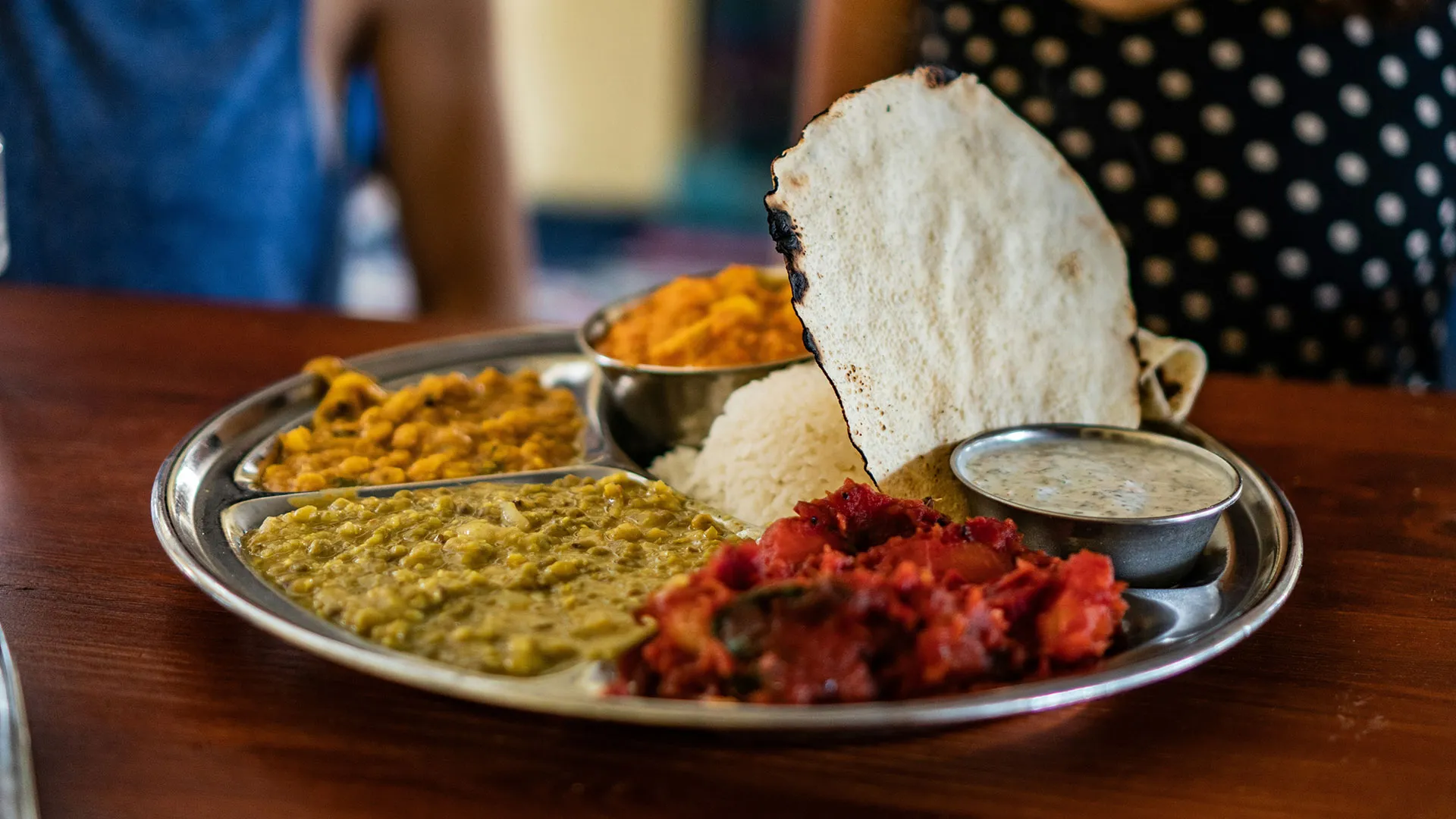 Sampler plate of red, green and yellow curries with pita bread and yogurt with za'atar