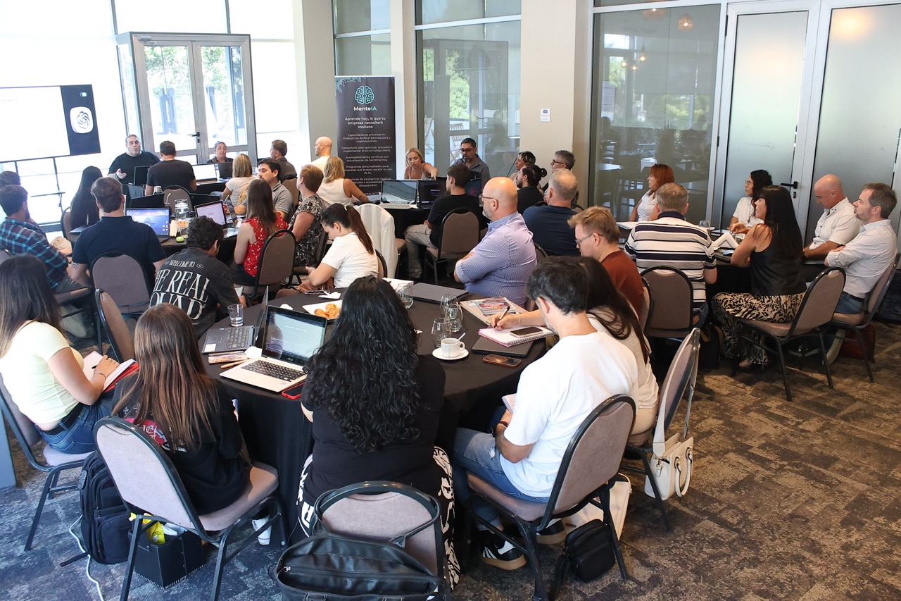 Vista general del salón en el Hotel Howard Johnson durante el entrenamiento práctico de Inteligencia Artificial. Se observa a los participantes trabajando con sus notebooks en mesas redondas, aplicando el método de MenteIA para optimizar sus procesos 