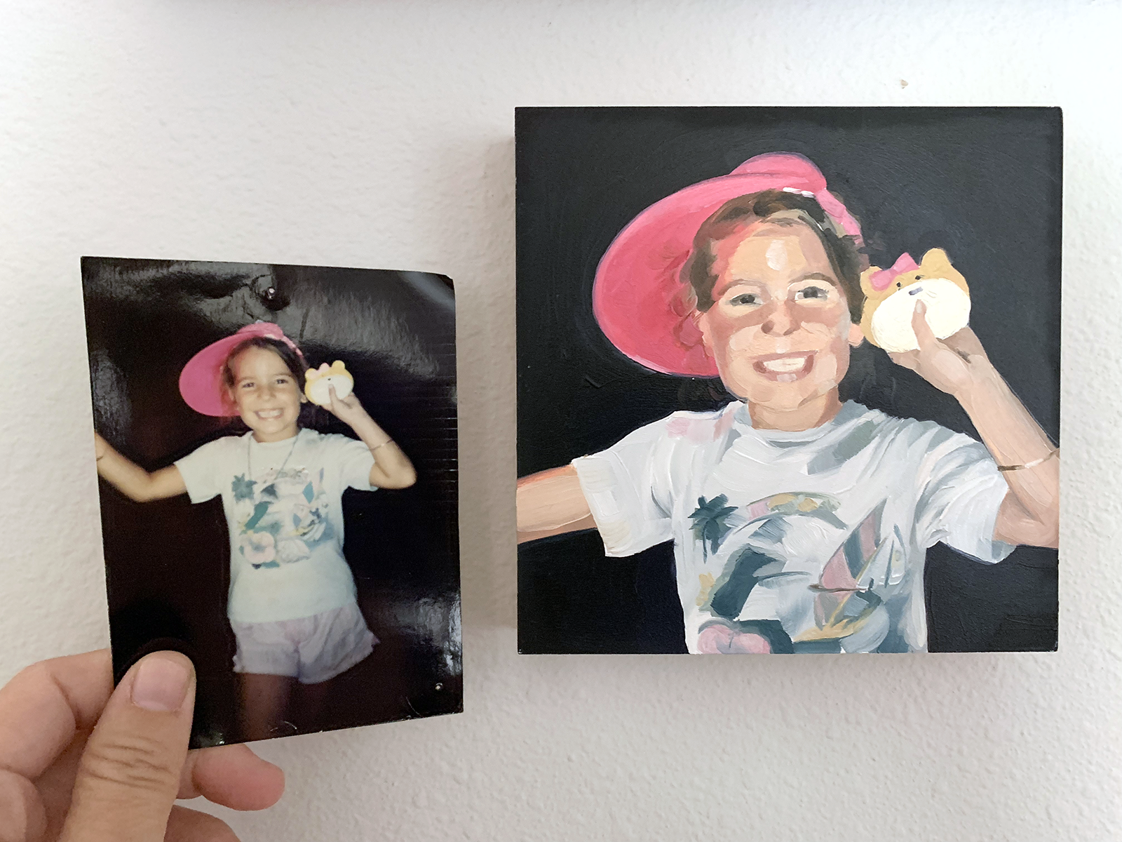 A photo-based commission beside its reference: an old snapshot of a child in a pink hat, held next to the finished oil portrait painted from it.
