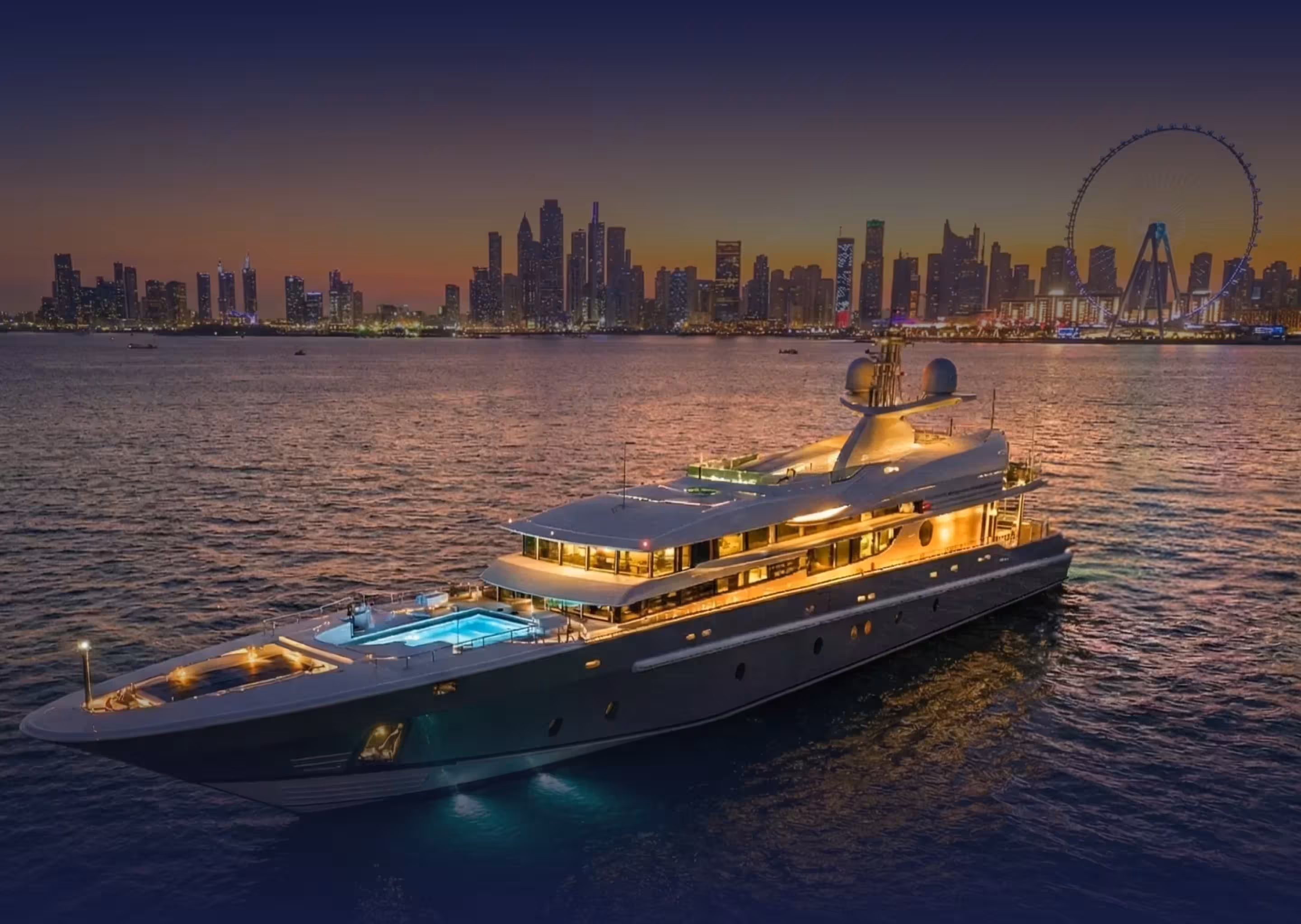 Luxurious yacht with illuminated pool sailing on water at sunset with a city skyline and large Ferris wheel in the background.