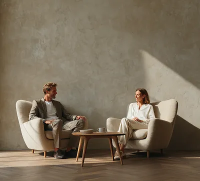 Two people seated in a bright, minimalist room with abundant natural light, showcasing refined spatial design and modern architectural aesthetics.