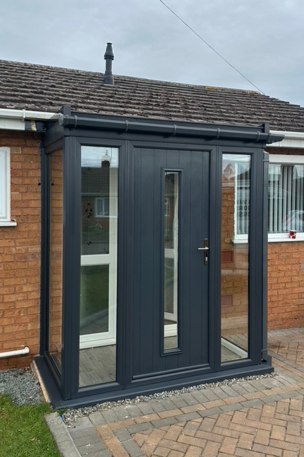 Modern dark gray porch with glass panels on a brick house front door.