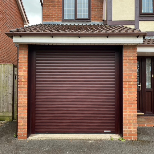 Closed brown roller garage door framed by a brick garage structure attached to a house.