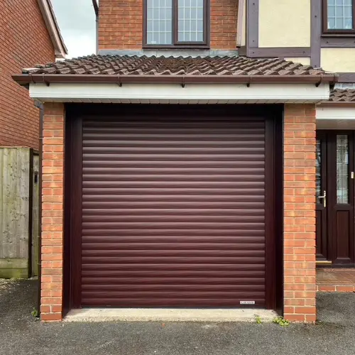Brown horizontal slatted garage door installed in a brick garage with tiled roof on a residential house.