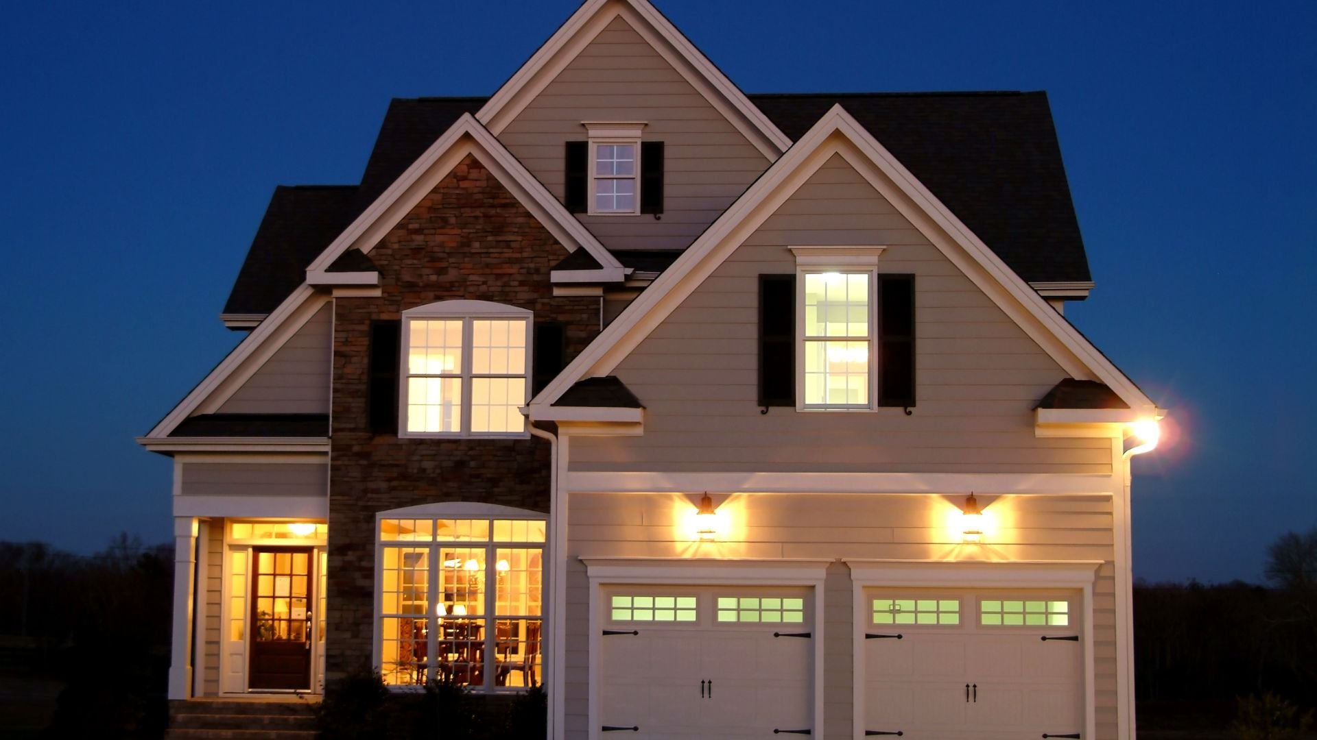 Warm, illuminated two-story house with stone accents at twilight
