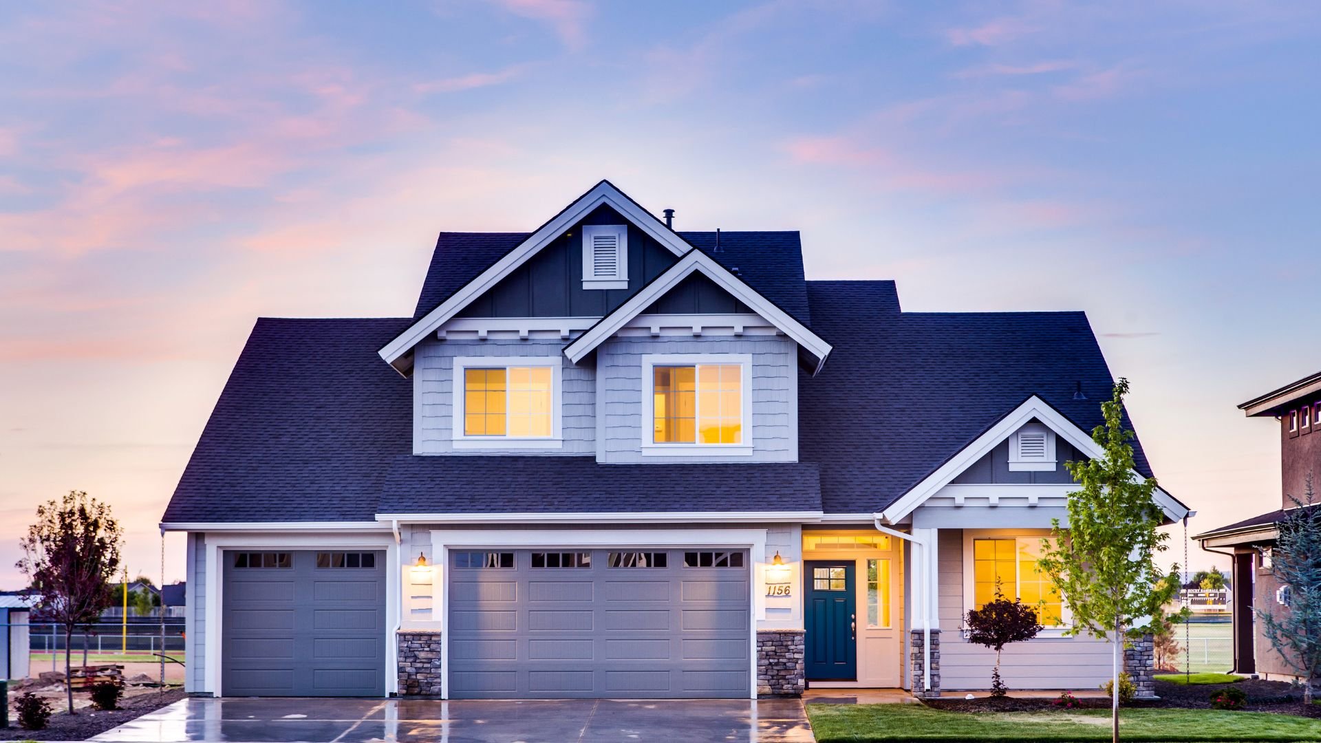 Modern suburban two-story house with three-car garage at twilight