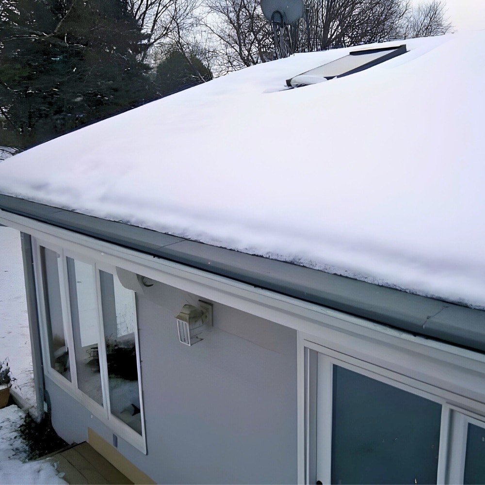 Snow-covered roof of a white building with windows on a winter day