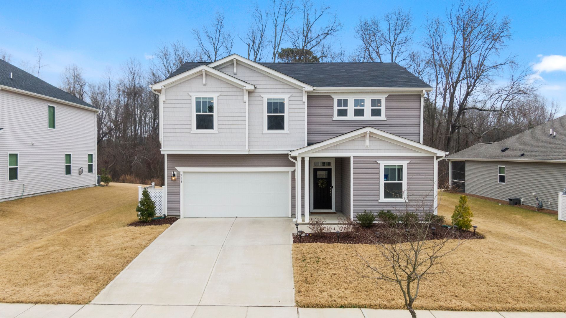 Modern two-story house with white garage, gray siding, and winter landscape