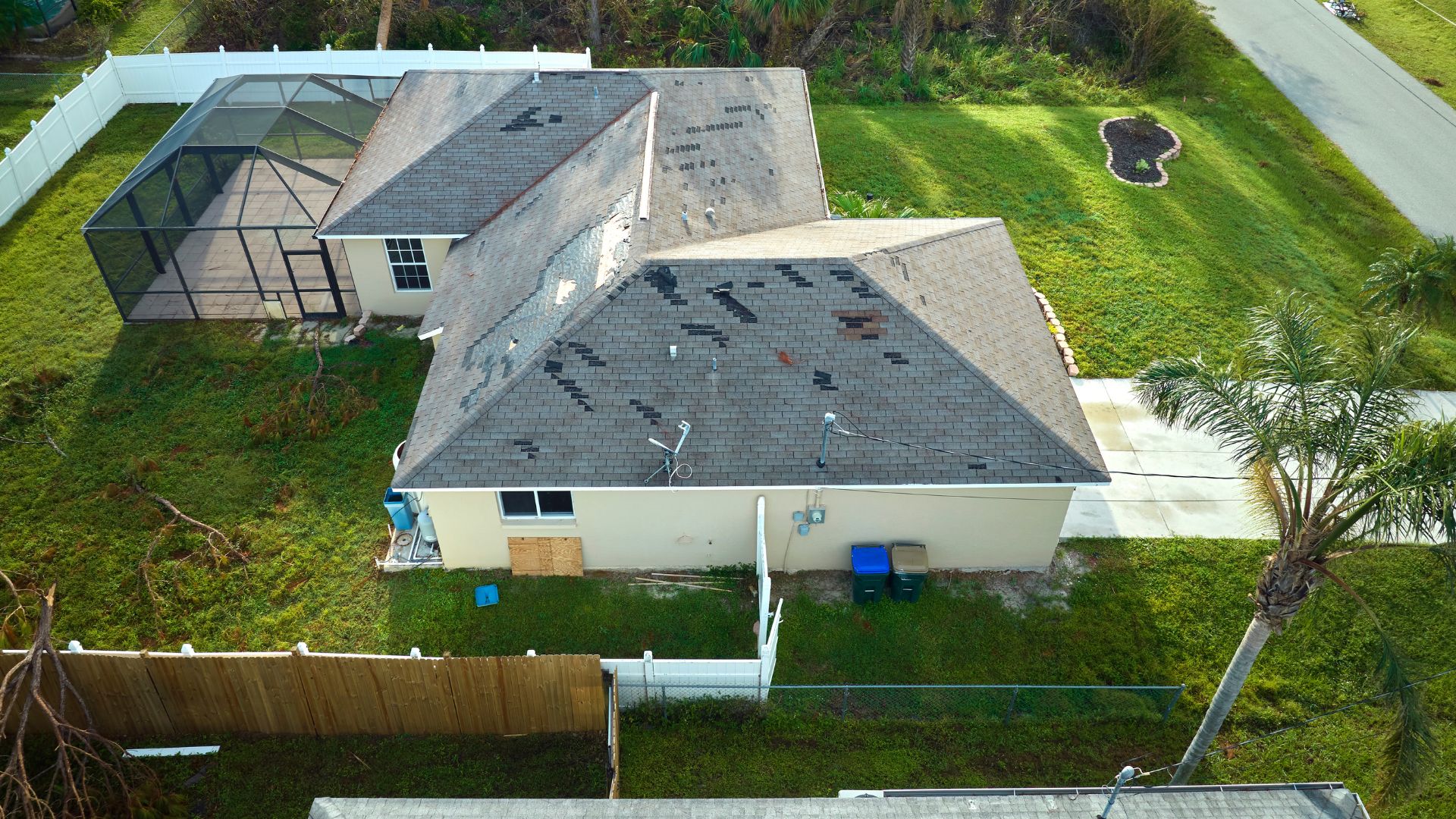Aerial view of damaged roof with missing shingles and boarded window