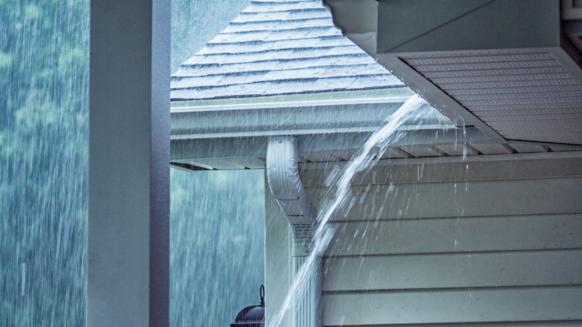 Heavy rain pouring off roof gutter during intense storm