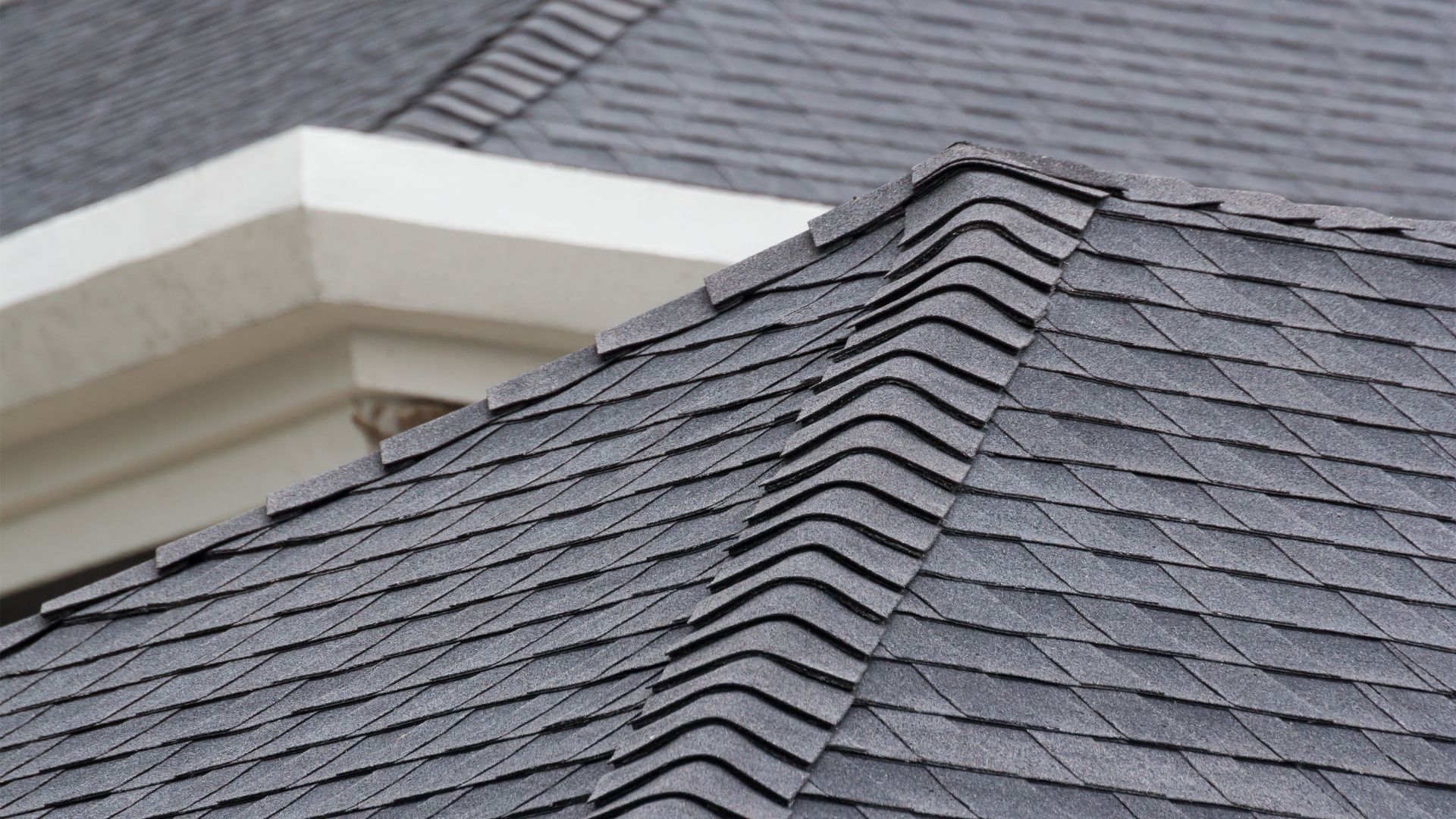 Gray asphalt shingles on a roof with architectural white trim detail
