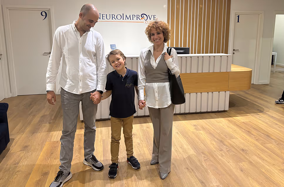 Criança acompanhada por dois adultos no espaço de receção da NeuroImprove.