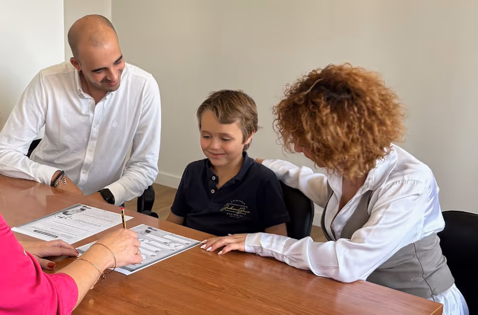 Criança acompanhada por adultos durante uma atividade de avaliação num ambiente clínico.