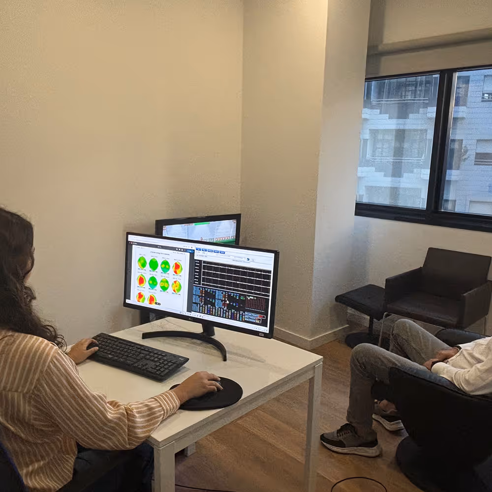 Profissional a analisar informação dos mapas cerebrais gerados pelo neurofeedback, num computador, num ambiente clínico.
