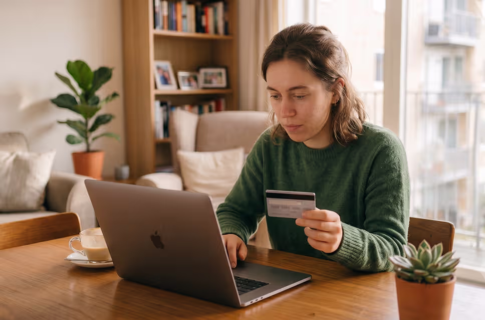 Mulher a segurar cartão multibanco enquanto insere os dados do mesmo no computador