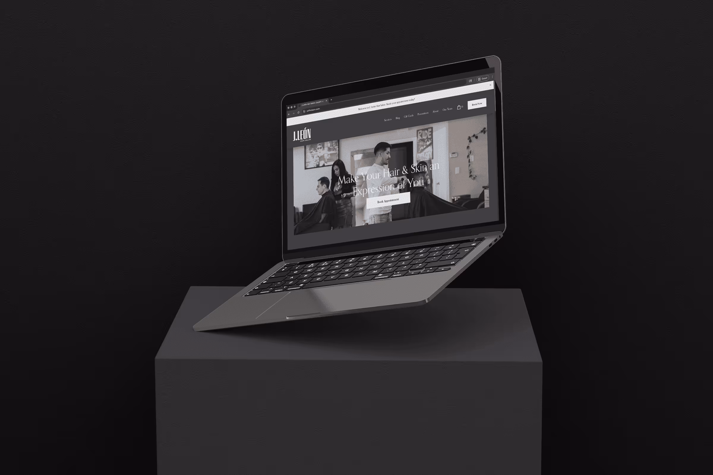 Gray laptop floating above a pedestal against a black background displaying a hair salon website homepage.