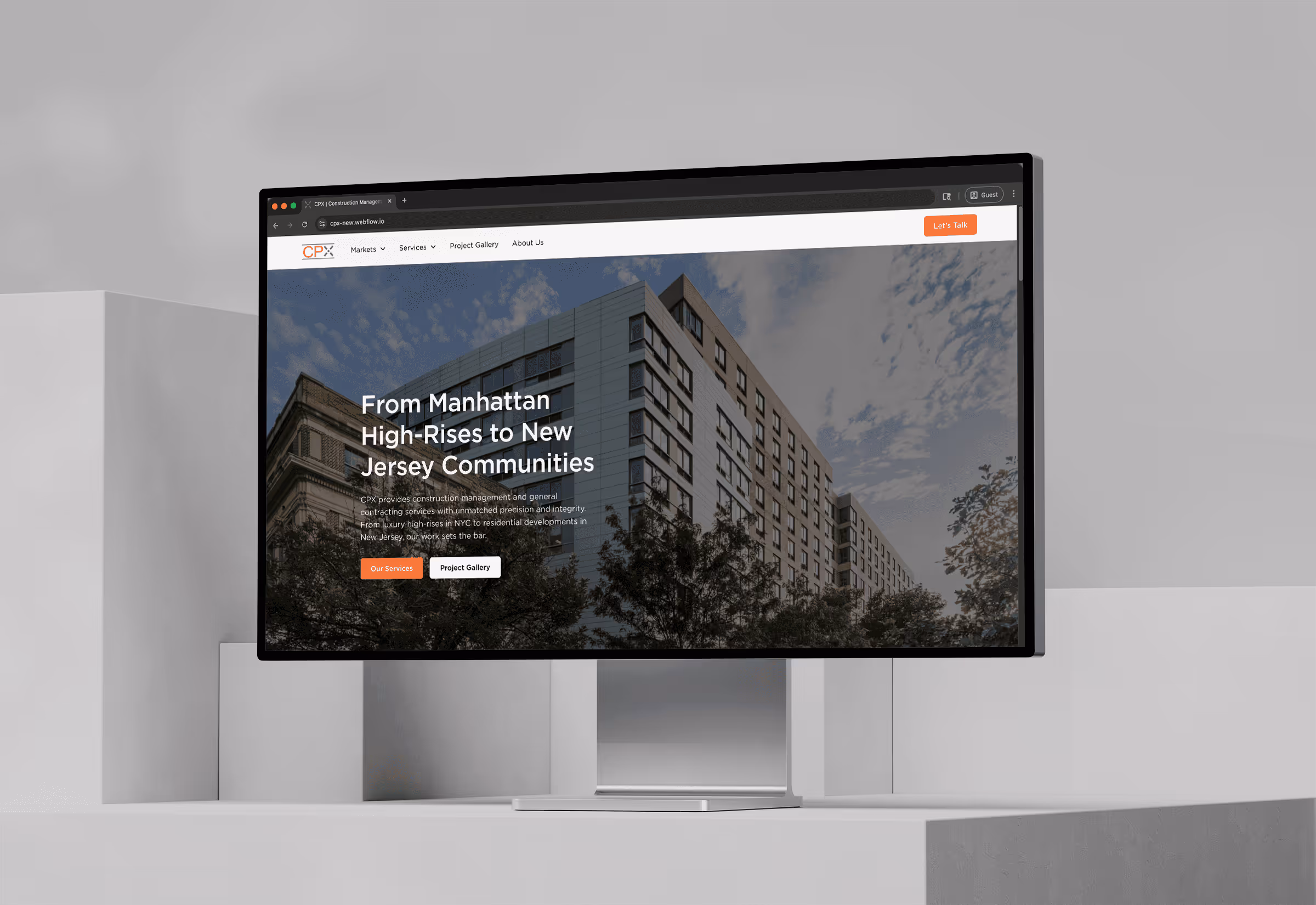 Computer monitor displaying a construction management website homepage with a city high-rise building background and text about services from Manhattan to New Jersey.