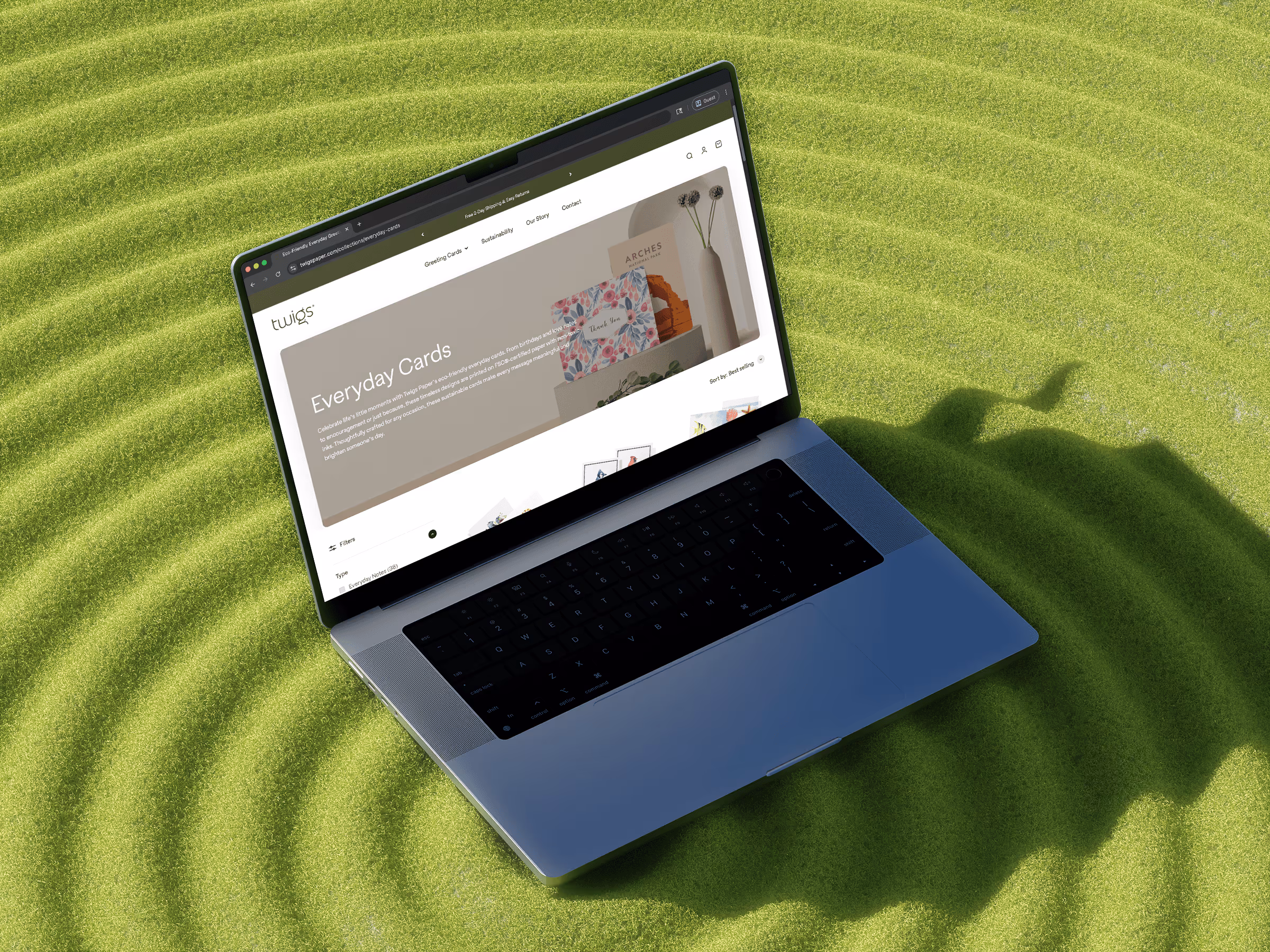 Open laptop on grass displaying a website selling everyday greeting cards from Twigs Paper.