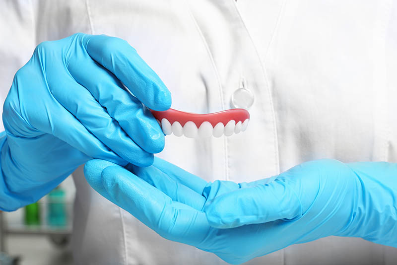 doctor holding dental bridge