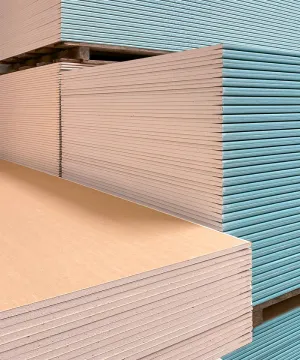 Close view of stacked drywall board edges, including moisture-resistant board