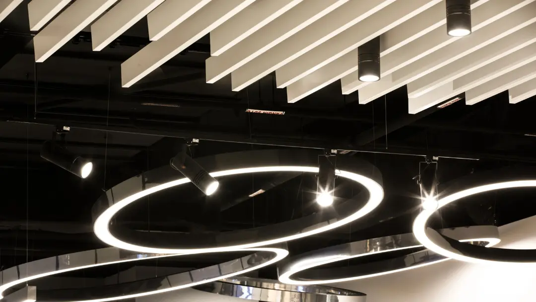 Suspended acoustic ceiling baffles above a dark commercial interior with ring pendant lighting