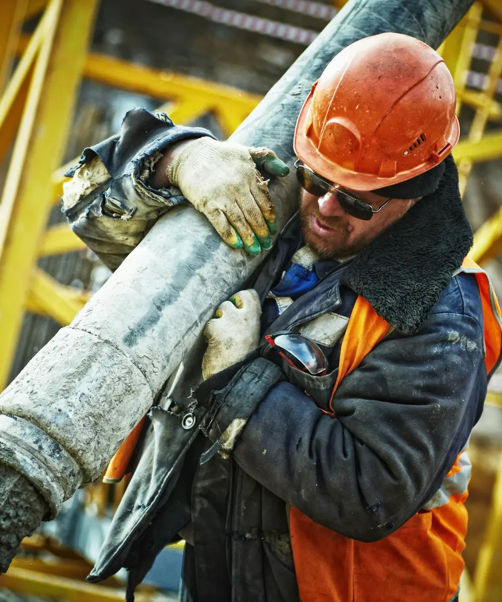 Construction worker in a hard hat and safety glasses carrying material on a jobsite