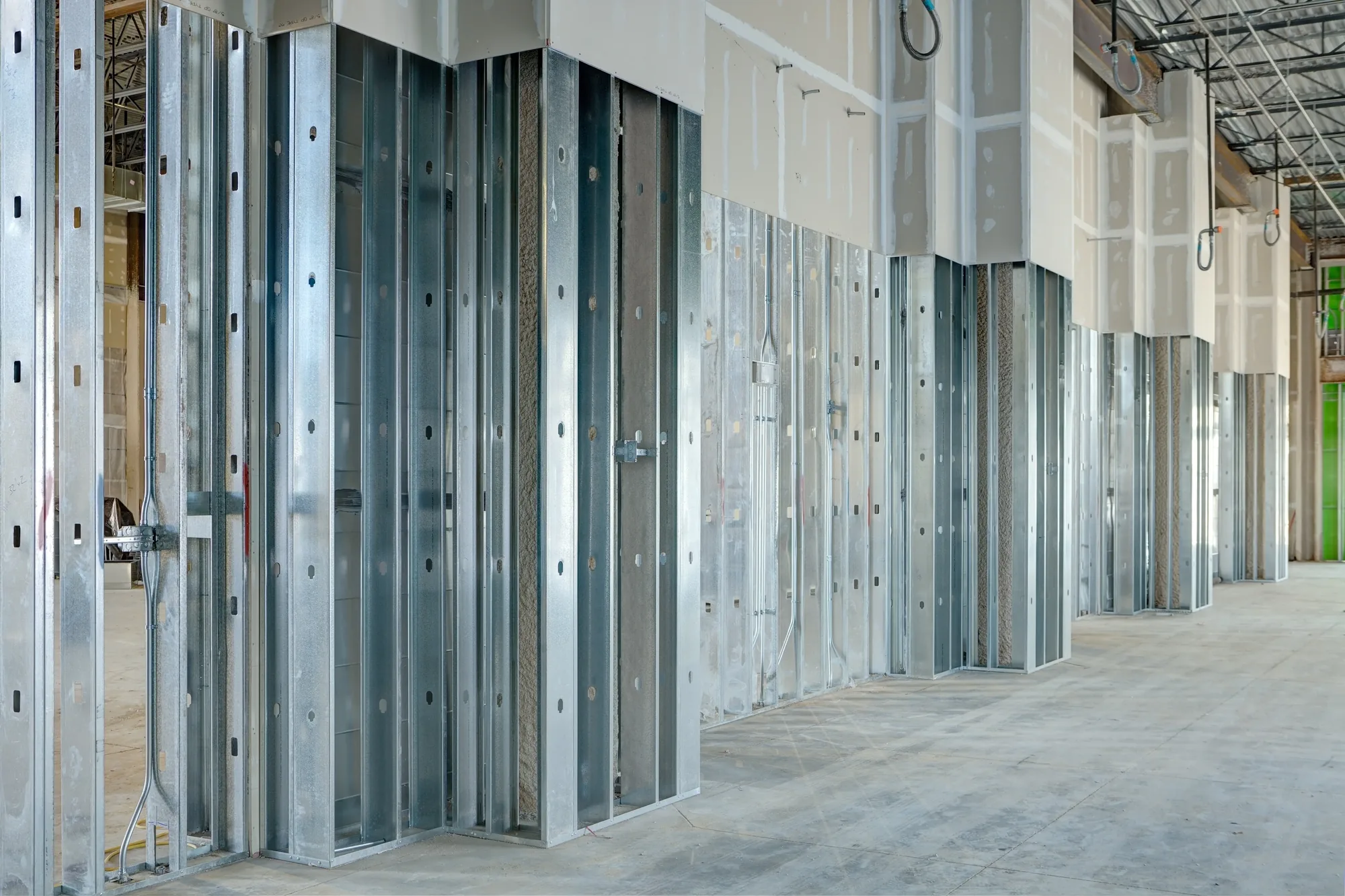 Rows of steel stud partitions framed out along a corridor before drywall board is hung