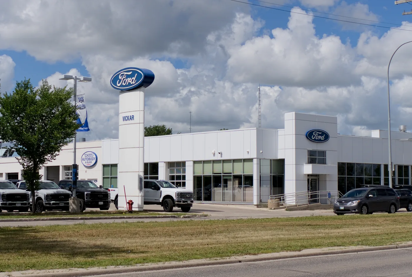 Parkside Ford pylon sign and showroom frontage in Winnipeg with new trucks parked outside