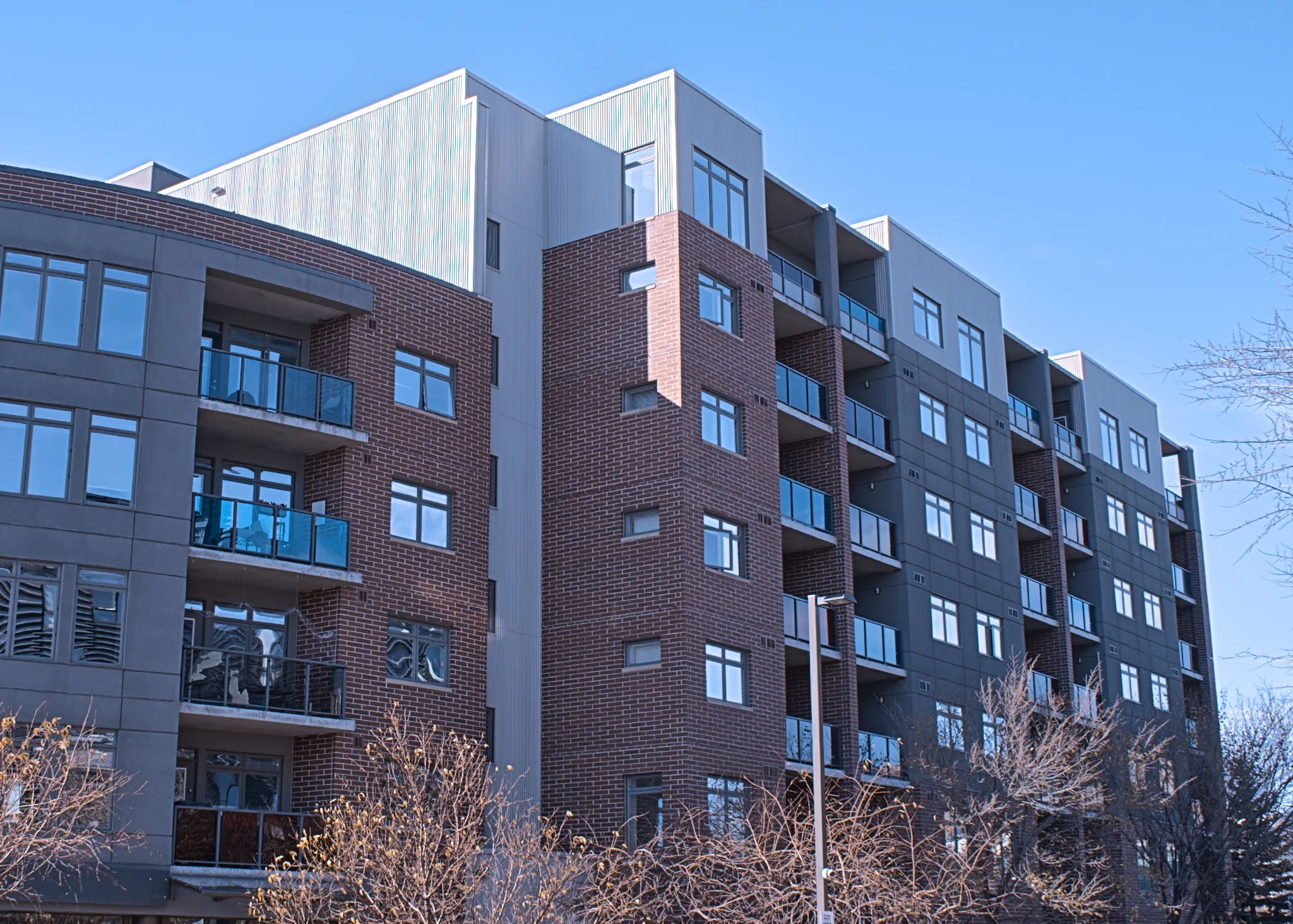 Brick and metal-panel elevation of the Waterfront Condominiums with glass balconies against a blue sky