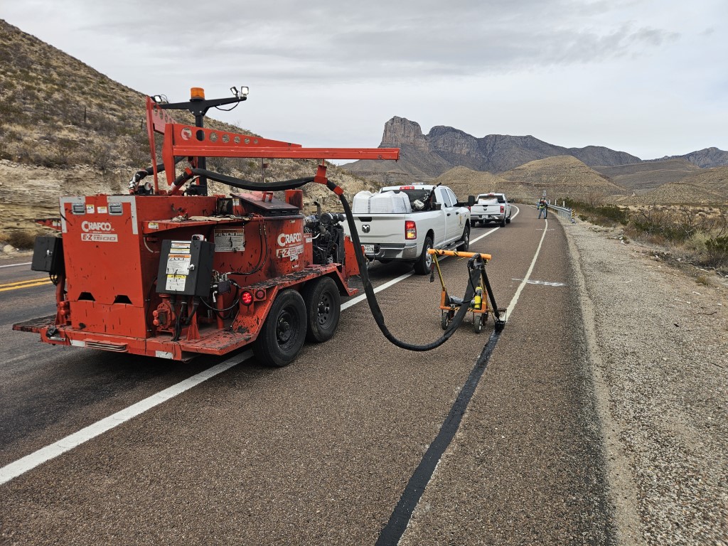 crafco EZ pour used to seal fiber line on a rural road with desert hills in the background.